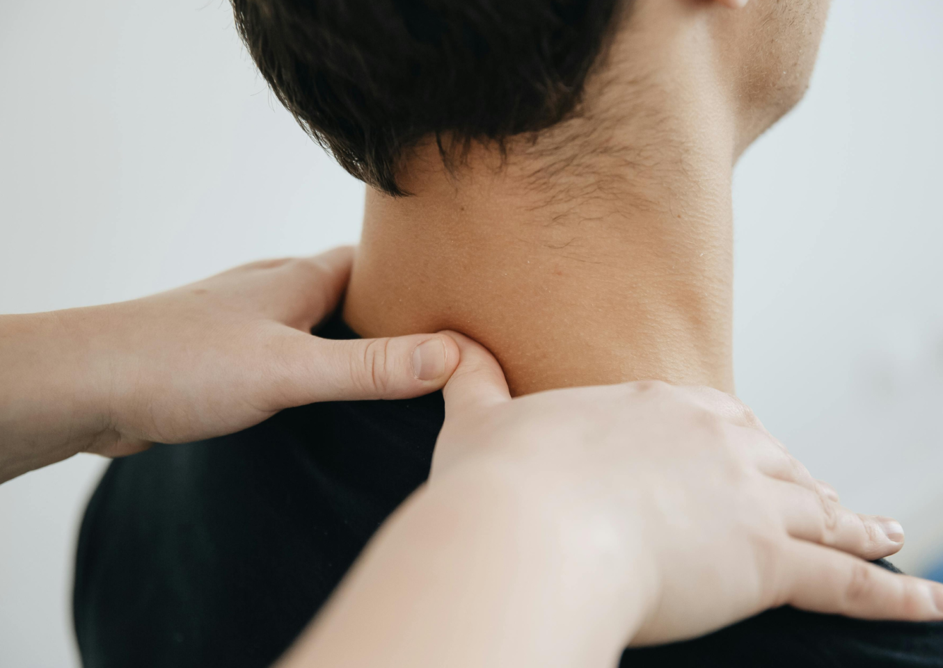 Kämmenet ovat henkilön hartioilla ja peukalot kaularangan alaosan kohdilla. Henkilö kuvattuna takaviistosta päin lapaluista kallonpohjaan asti.